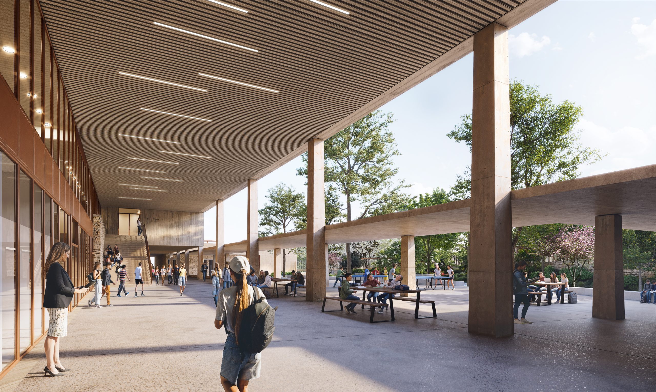 Cour de récréation d'un établissement scolaire sous un grand préau couvert en béton, avec élèves et tables de pique-nique.